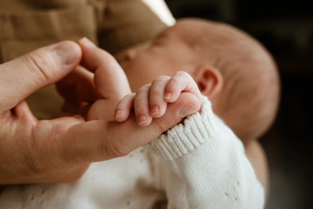 La petite main d’un nouveau-né serrant le doigt de son parent