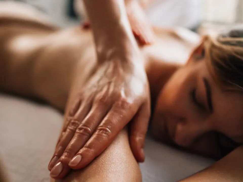 Un geste de massage bien-être sur l’épaule d’une femme au repos