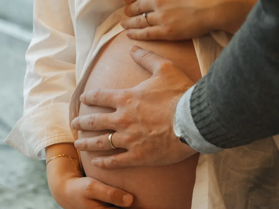 Les mains de futurs parents posées sur un ventre de grossesse